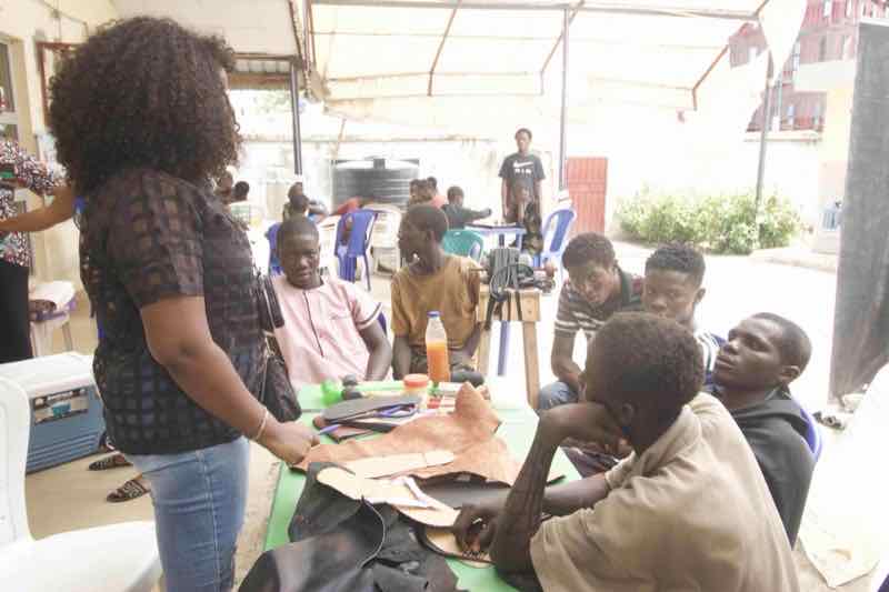 Young people learning cobbling skills from experienced craftsman